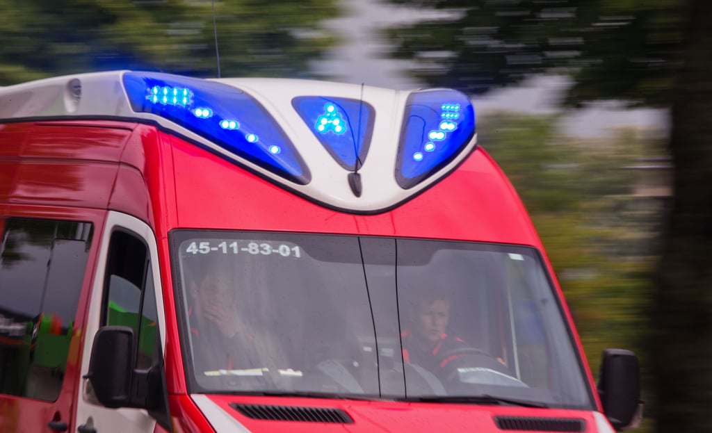 Ein Rettungswagen fährt mit Blaulicht zu einem Krankenhaus.