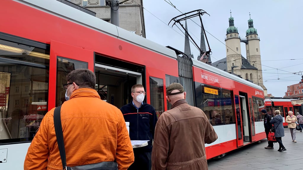 Felix Baumann, Leiter der Fahrgastinformationen bei der Havag, spricht mit Passanten vor der Info-Tram auf dem Markt über die Bauarbeiten und ihre Konsequenzen im Böllberger Weg.