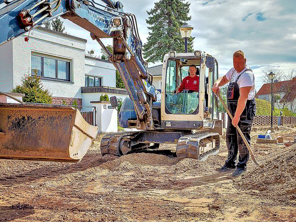 Matthias Jahnke (im Bagger) und Andy Ulok sind gerade dabei, Arbeiten am Unterbau der Hermann-Ebel-Straße in Gommern auszuführen. Die Arbeiten werden noch bis voraussichtlich Juli andauern. Ein Grund dafür sind Lieferprobleme bei Baumaterialien.