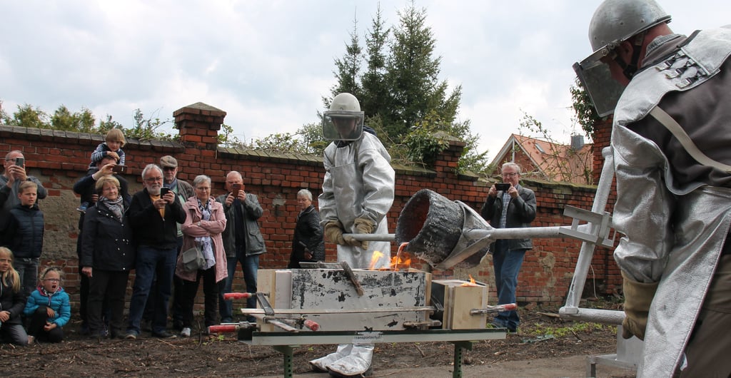 Bildhauer Klaus Cenkier (rechts) und sein Assistent Marek Dreihaupt (13) gießen den über 1000 Grad Celsius heißen Bronzeguss in die vorbereiteten Formen.