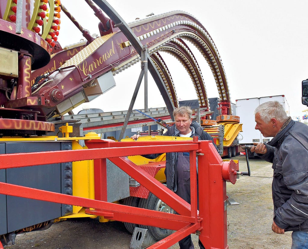 Der hallesche Schausteller Heinz Meyer (Mitte) und Dennis Seibicke bauen das Fahrgeschäft „Spider“ auf.