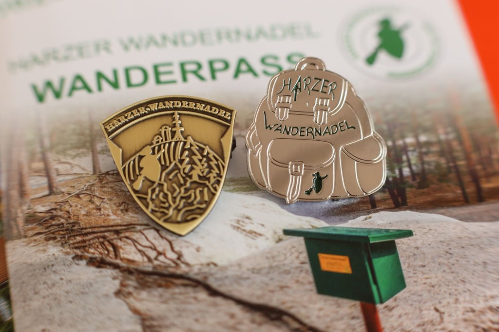 Abzeichen der Harzer Wandernadel liegen auf einem Stempelheft.