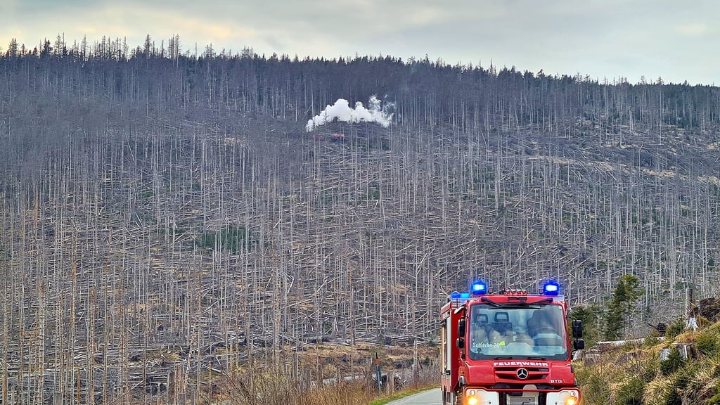 Ein Wagen der Schierker Feuerwehr fährt nach seinem Einsatz die Brockenstraße herab, während im Hintergrund  noch Kameraden gegen den Waldbrand zwischen Eckerloch und Goethebahnhof kämpfen.