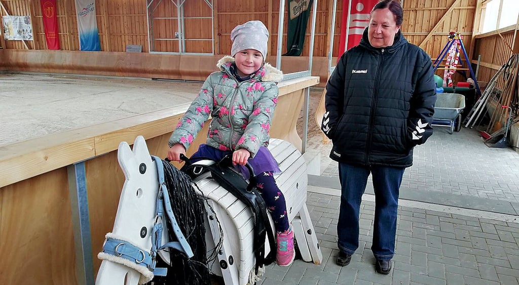 Vor allem beim Nachwuchs ist Reiten sehr beliebt. Die kleine Leni auf einem Holzpferd und Oma Katrin Stalive schaut zu.