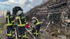 Feuerwehrleute stehen vor einem abgebrannten Waldstück am Brocken auf den Gleisen.
