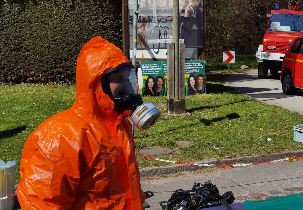 Ein Feuerwehrmann im ABC Schutzanzug steht in der Nähe der Freilichtbühne in Lübeck, wo es einen Zwischenfall gegeben hat. Auf dem Areal hätte nachmittags eine Wahlkampfveranstaltung von Bündnis 90/Die Grünen mit Spitzenkandidatin Heinold und Außenministerin Baerbock stattfinden sollen. Die Ermittlungen laufen. Foto: Volker Gerstmann/TNN/dpa/