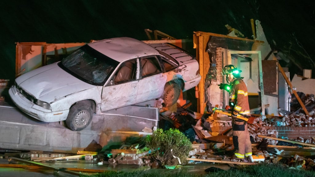 Ein Feuerwehrmann steht vor einem stark beschädigten Auto und Haus in Andover im Gebiet Kansas, nachdem ein Tornado durch das Gebiet östlich von Wichita gezogen ist.