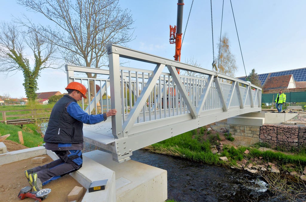 Passgenau wird die elf Meter lange Aluminiumbrücke für Fußgänger auf die neuen Widerlager gesetzt. Natürlich von Regina Mathies, deren Namen die Brücke auch trägt.