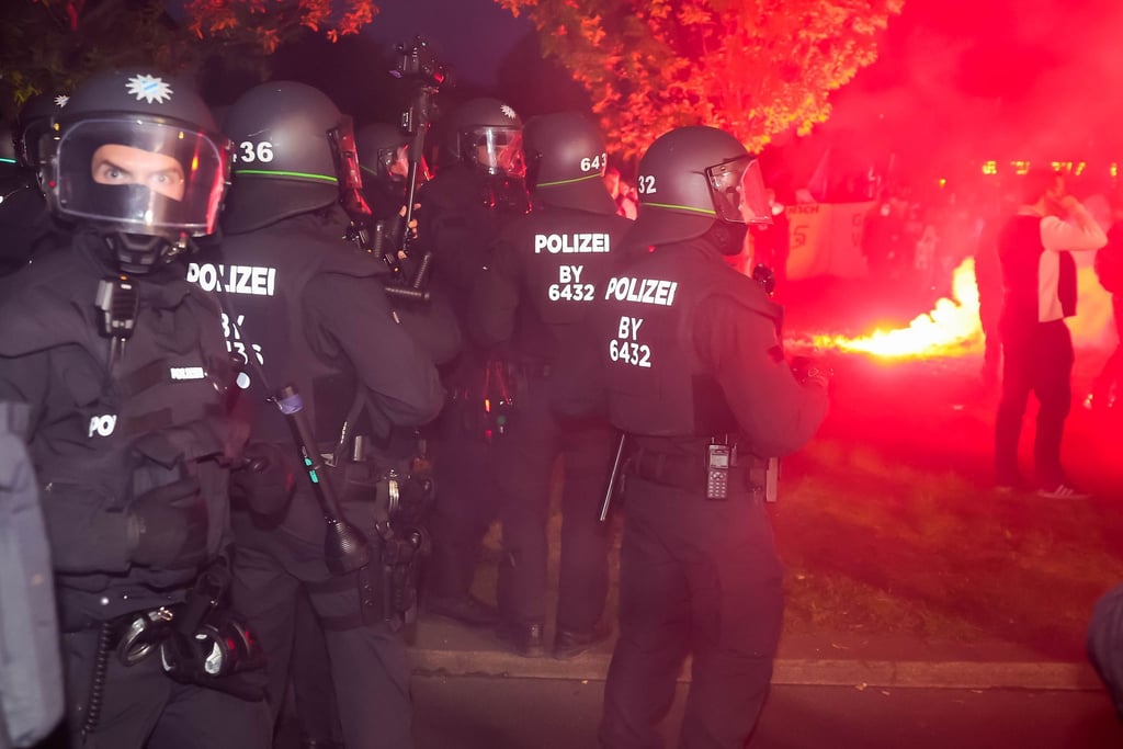 Polizisten bei der „Revolutionären 1. Mai-Demonstration“ in der nähe eines brennendes Bengalos in Berlin.