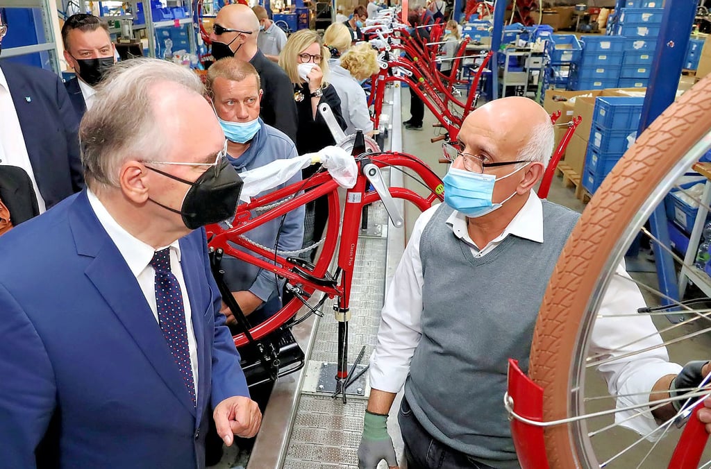 Ministerpräsident Reiner Haseloff (links) im Gespräch mit dem aus Syrien stammenden Mhd Belal Albezrah  am Montageband von Zweirad-Union.