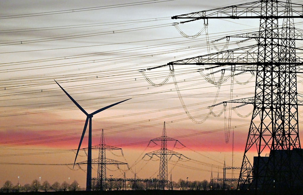Strommasten und Windräder im Sonnenuntergang. Die Sorgen im Salzlandkreis ob der steigenden Energiepreise nehmen zu. Der Salzlandkreis plant mit Mehrausgaben von 1,6 Millionen Euro allein für dieses Jahr.