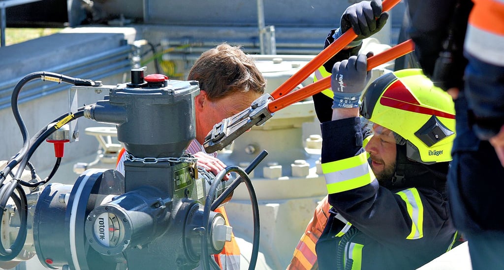 Ein Feuerwehrmann löst mit dem Bolzenschneider den Umweltaktivisten Michael Winter von der Pumpstation bei Elbeu.