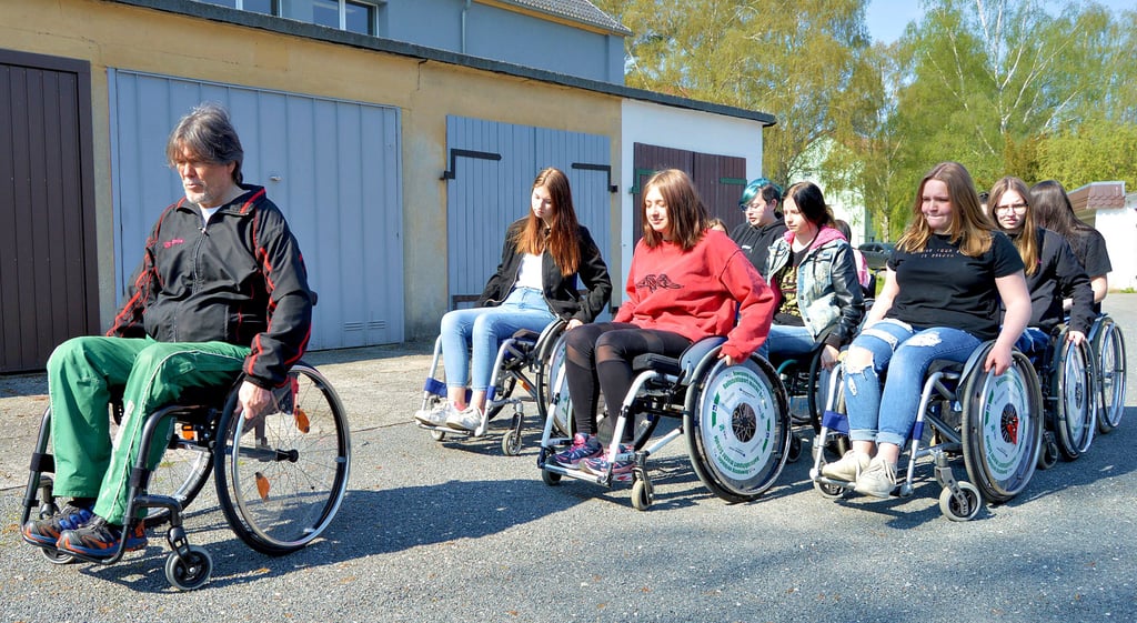 Unter Anleitung von Projektkoordinator Volker Möws lernen die Schülerinnen der 8c, wie man sich im Alltag mit einem Rollstuhl fortbewegt.