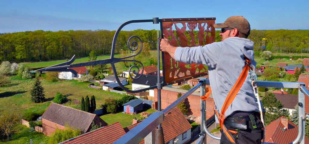 René Leßmann von der Dachdeckerfirma Schneider aus Wulkau bringt in knapp 30 Metern Höhe die Teile der Bekrönung auf dem Kamernschen Kirchturm an, hier die 1933 von Willi Carben gestifteten Wetterfahne.