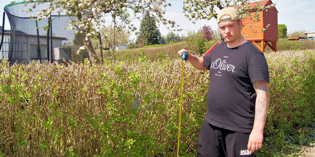 Erik Seibecke traute seinen Augen kaum, als er in seinen Kleingarten kam: Die Hecke war ohne sein Wissen um einen halben Meter auf Initiative des Vereinsvorsitzenden gekürzt worden. Welche Befugnisse haben Kleingärtner, Kleingartenvereine und was ist der Preis für den niedrigen Pachtzins?