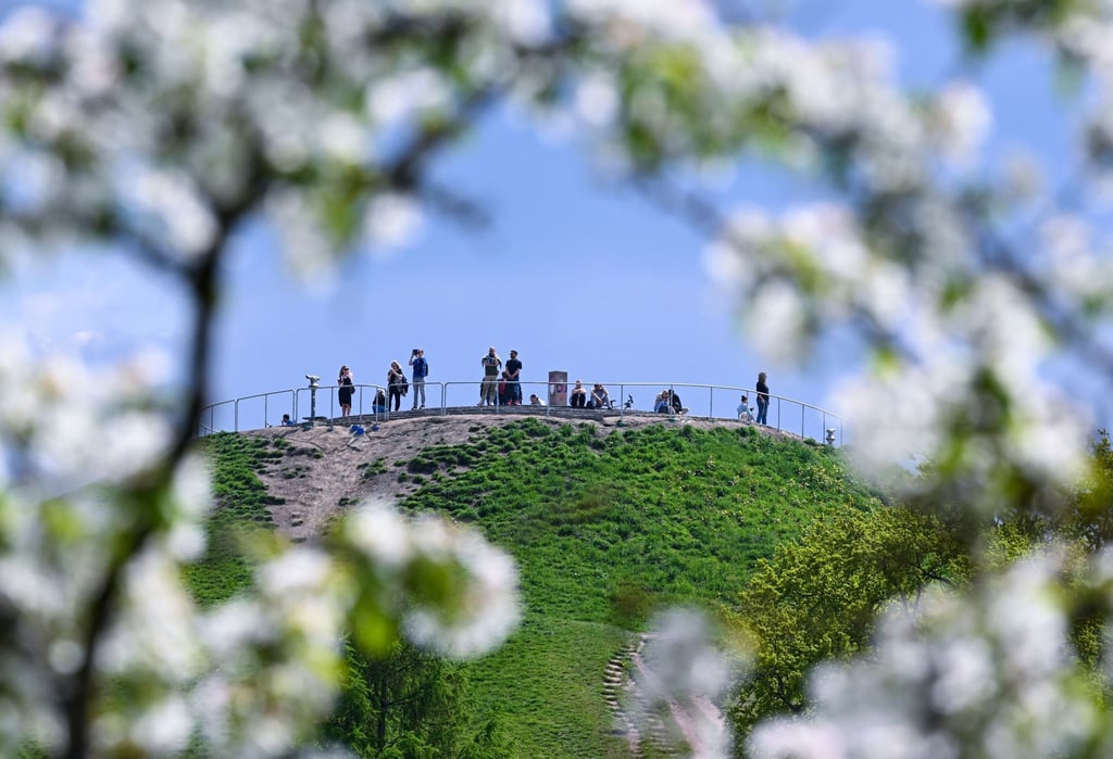 Ausflügler auf dem Olympiaberg in München erfreuen sich der Sonne.