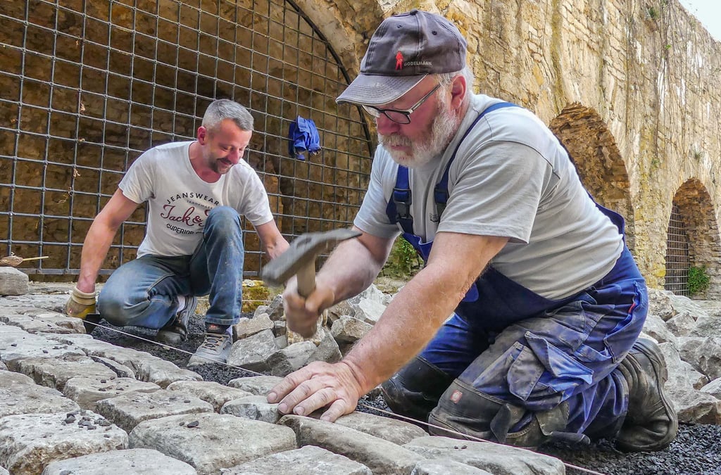 Mitarbeiter der Bauhütte Querfurt pflastern die Burg. Die Steine sind historisch, sie lagerten in den vergangenen Jahren auf der Baustelle.