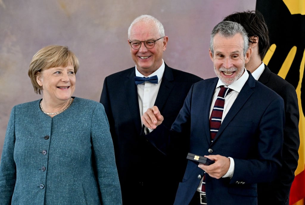 Angela Merkel (l-r), Autor Jean-Claude Kuner und der Verdienstkreuzträger Ulrich Matthes im Schloss Bellevue.
