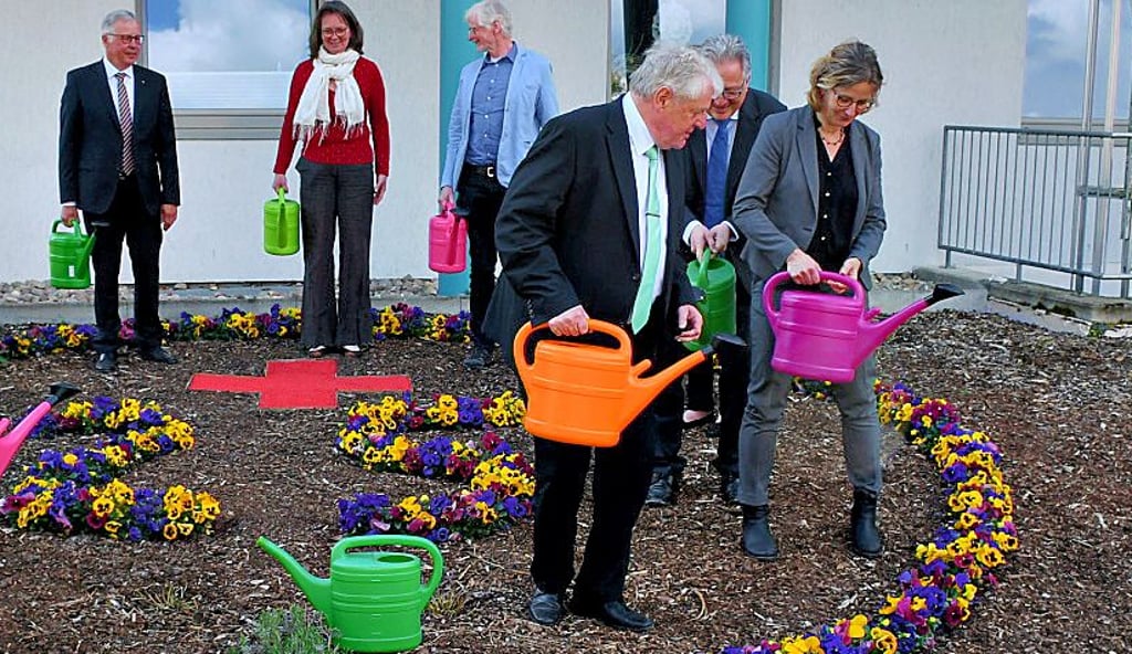 Teilnehmer der Festveranstaltung gossen ein Blumenbeet mit einer 25.