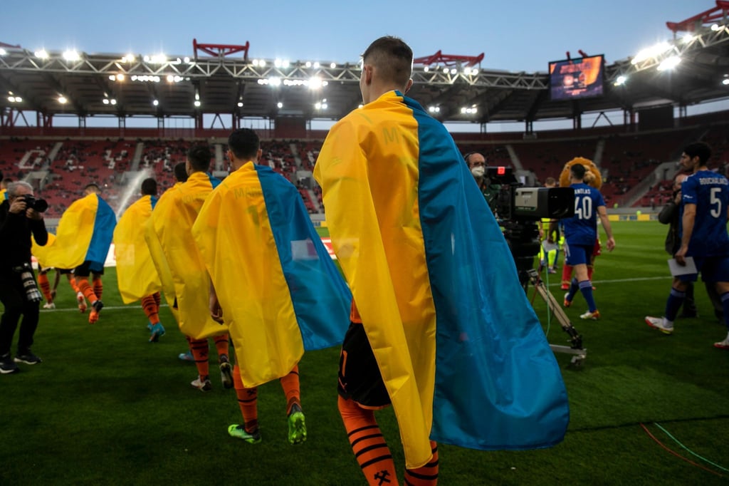 Schachtjor-Spieler (l) betreten für ein Benefizspiel gegen Olympiakos Piräus den Rasen. Die Saison in der Ukraine ist abgebrochen worden.