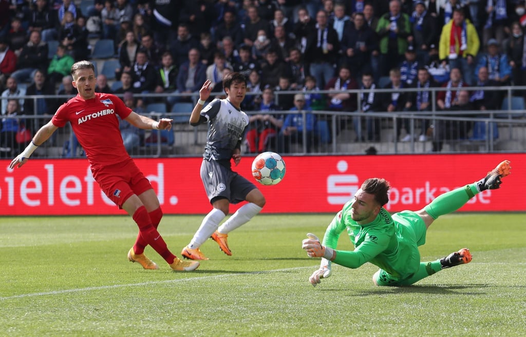 Berlins Torwart Marcel Lotka (r) pariert einen Ball von Bielefelds Masaya Okugawa (2.v.l).