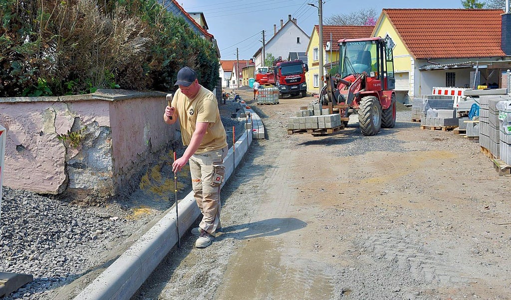    Bauarbeiter Mark Schippel beim Verlegen von Straßenborden an der Ortsdurchfahrt in Hergisdorf 