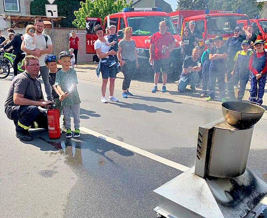 Michael Wichmann zeigt den Kindern, wie man den Feuerlöscher betätigt.