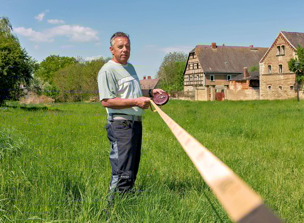 Der Wetterzeuber Bürgermeister Frank Jacob zeigt mit dem Maßband, wie nahe der neue Funkmast an den Häusern ist Katersdobersdorf stehen soll. Sein Fazit: zu nah. Deshalb ist er gegen den Neubau.