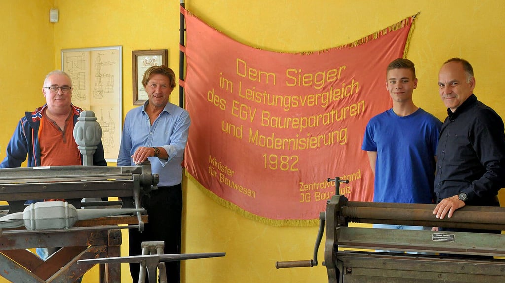 Lebendige Geschichsstunde: Heiko Paul, Olaf Pleitz, Dustin Neumann und Uwe Gering (v.l.) stehen am roten Ehrenbanner, das dem damals volkseigenen Betrieb 1982 für exzellente Arbeit verliehen wurde.