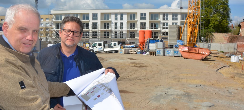 BWG-Vorstand Heino Näth und Mitarbeiter Lutz Roenspieß mit den Plänen für den Wohnkomplex Luther-Straße/Gartenstraße. Im Hintergrund der erste Rohbau des ersten Wohngebäudes.