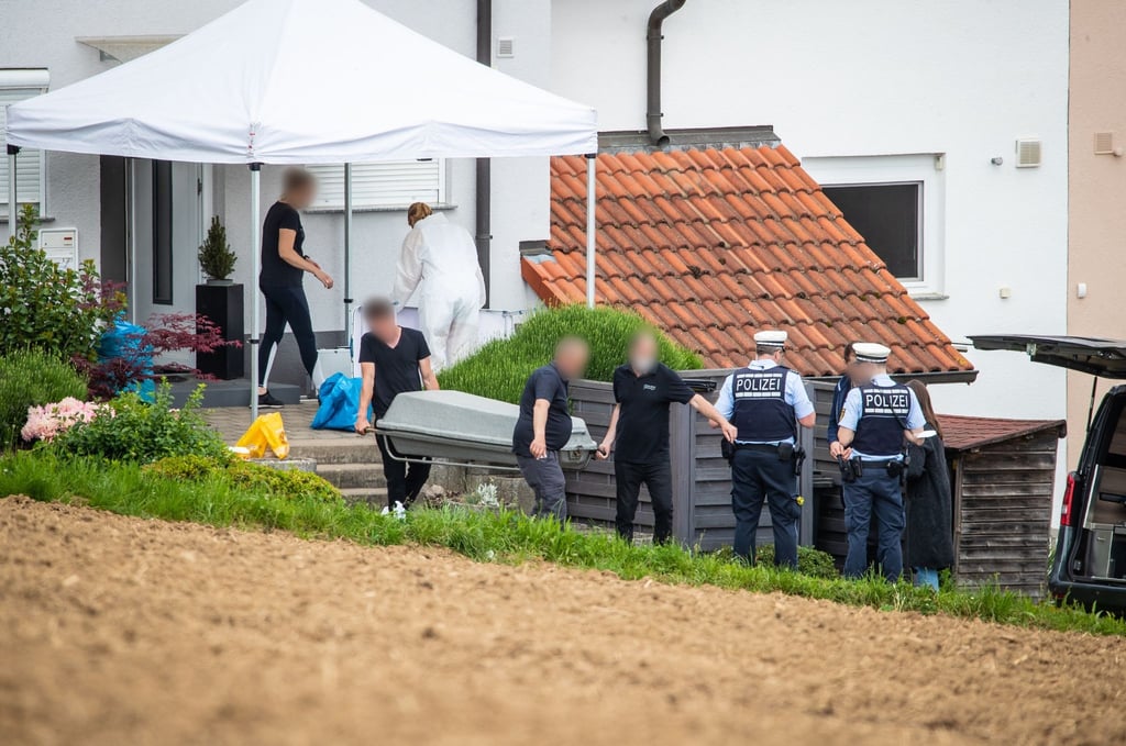 Männer transportieren einen Sarg in einen Leichenwagen.