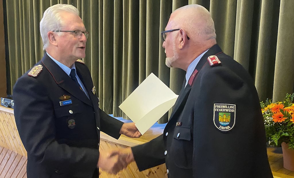 Der stellvertretende Landesbrandmeister Roland Karthäuser überreicht Rainhard Reinelt (re.) in Zahna die Ehrenspange der Feuerwehr im Auftrag der Innenministerin Tamara Zieschang, die die Urkunde dazu unterzeichnet hat.