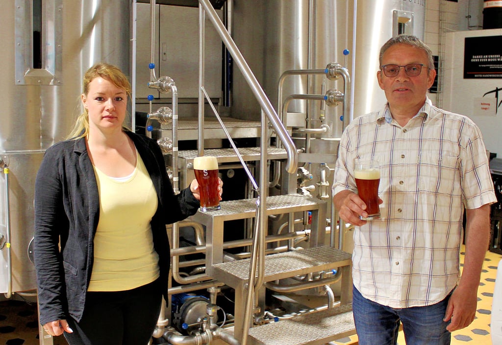 Restaurantleiterin Maria Gehr und Seniorchef Armin Schulz erklären vor der Brauanlage in Tangermünde, warum das Bier teurer wird.