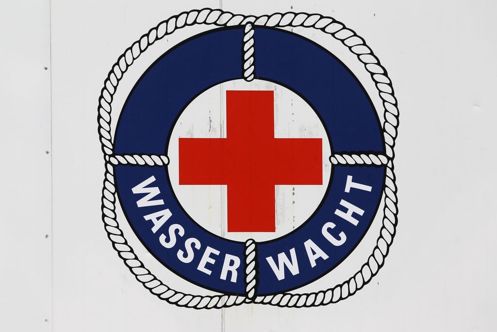 Das Logo der Wasserwacht des DRK an einem Rettungsturm im Ostseebad Warnemünde. Bis September halten die Rettungsschwimmer an bis zu zwölf Türmen Wache.