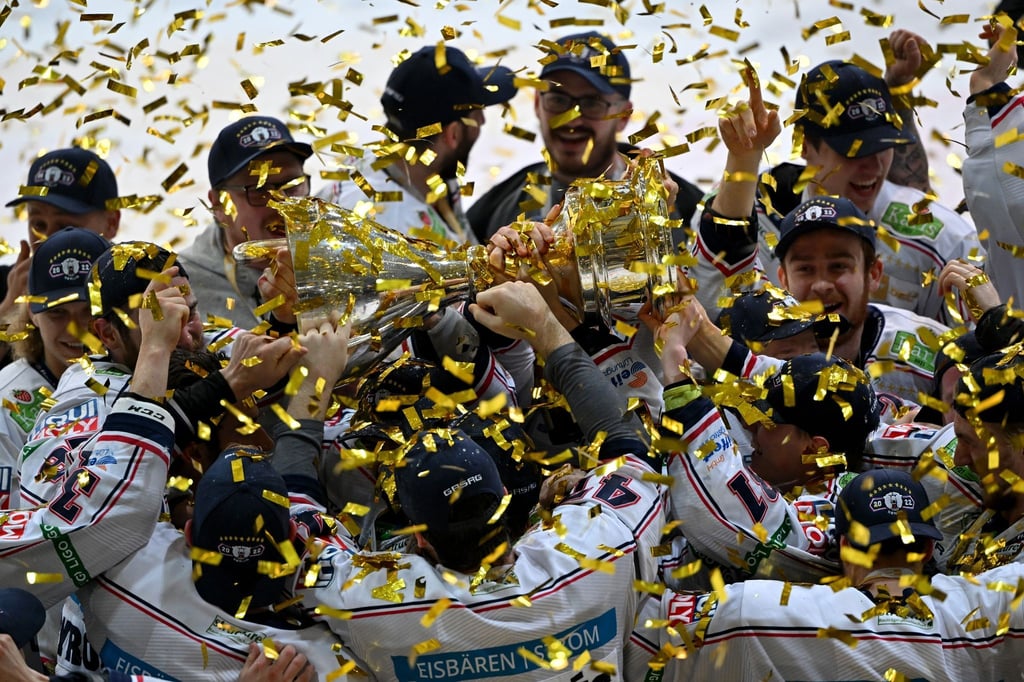 Die Eisbären Berlin jubeln nach dem Finalsieg mit dem Pokal im Konfettiregen.