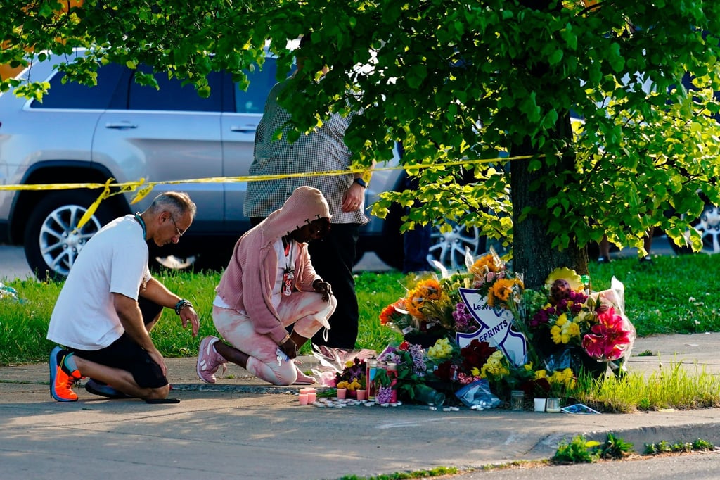 Menschen knien vor Blumen, um den Opfern tödlicher Schüsse in einem Supermarkt in Buffalo die letzte Ehre zu erweisen.