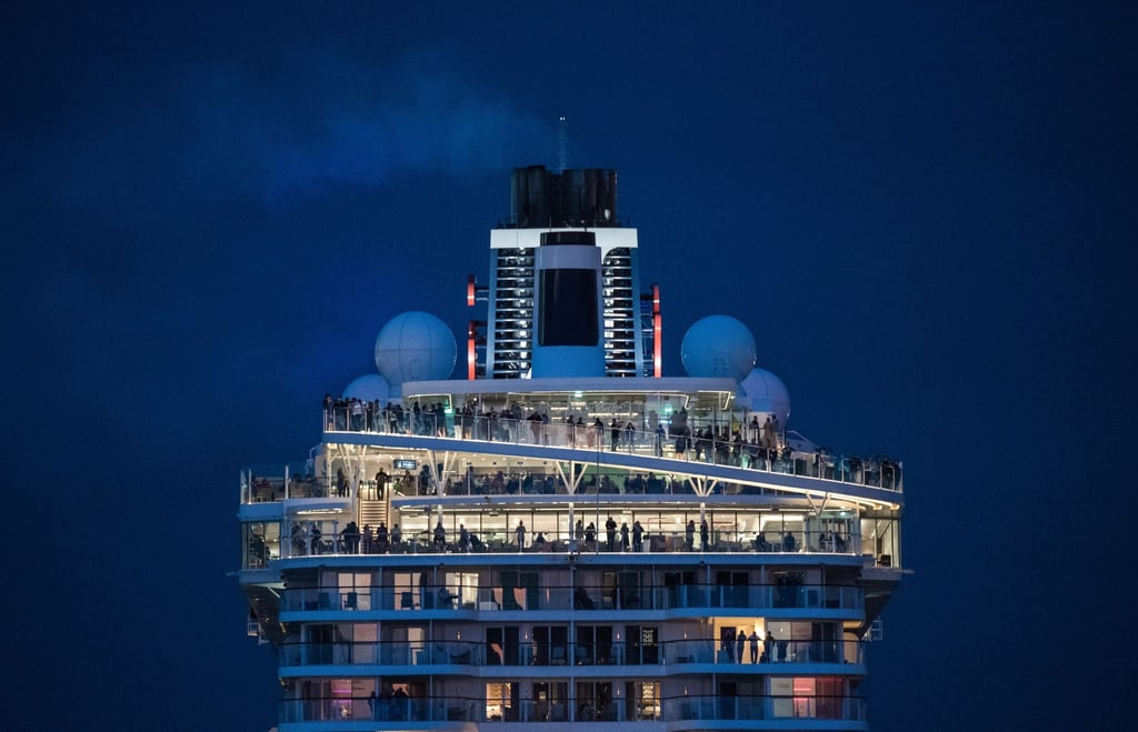 Passagiere verfolgen an Bord eines Kreuzfahrtschiffs das Auslaufen aus dem Hafen.