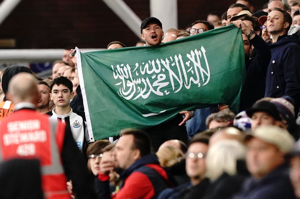 Ein Fan von Newcastle United hält die Fahne von Saudi-Arabien während eines Spiels hoch.