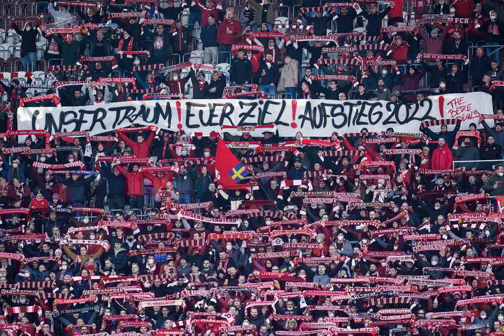 Fans des 1. FC Kaiserslautern halten ein Transparent mit der Aufschrift „Unser Traum! Euer Ziel! Aufstieg 2022!“ in die Höhe.
