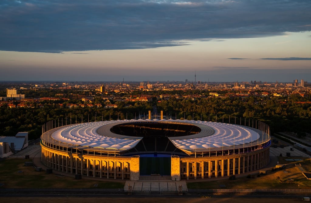 Die untergehende Sonne scheint auf das Olympiastadion in Berlin.