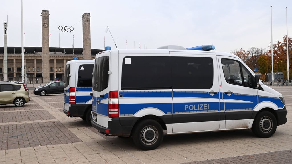 Polizeiautos stehen vor dem Berliner Olympiastadion, um ein Fußballspiel abzusichern.