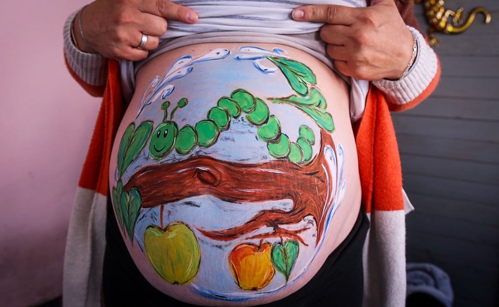 Die Hobbymalerin Marienn Pyko hat der Schwangeren Sandra Genz eine kleine hungrige Raupe auf den Babybauch gemalt.