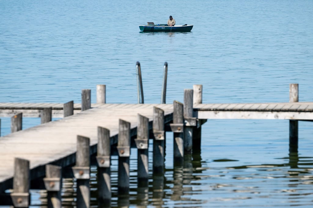 Ein Mann auf seinem Ruderboot angelt auf dem Ammersee in der Bucht von Herrsching. Mitte der Woche könnten es in manchen Orten Bayerns an die 30 Grad warm werden.
