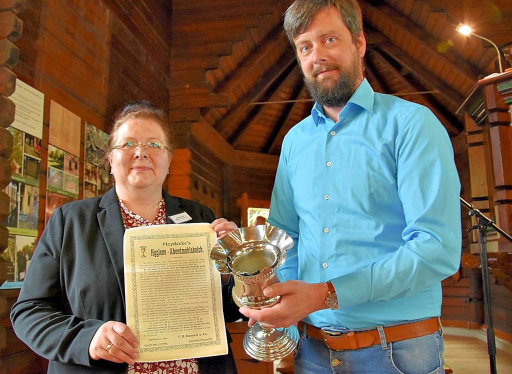Pfarrer Karsten Höpting hat einen Abendmahlskelch aus dem Albrechtshaus mitgebracht und Vereinssprecherin Cosima Pilz übergeben.
