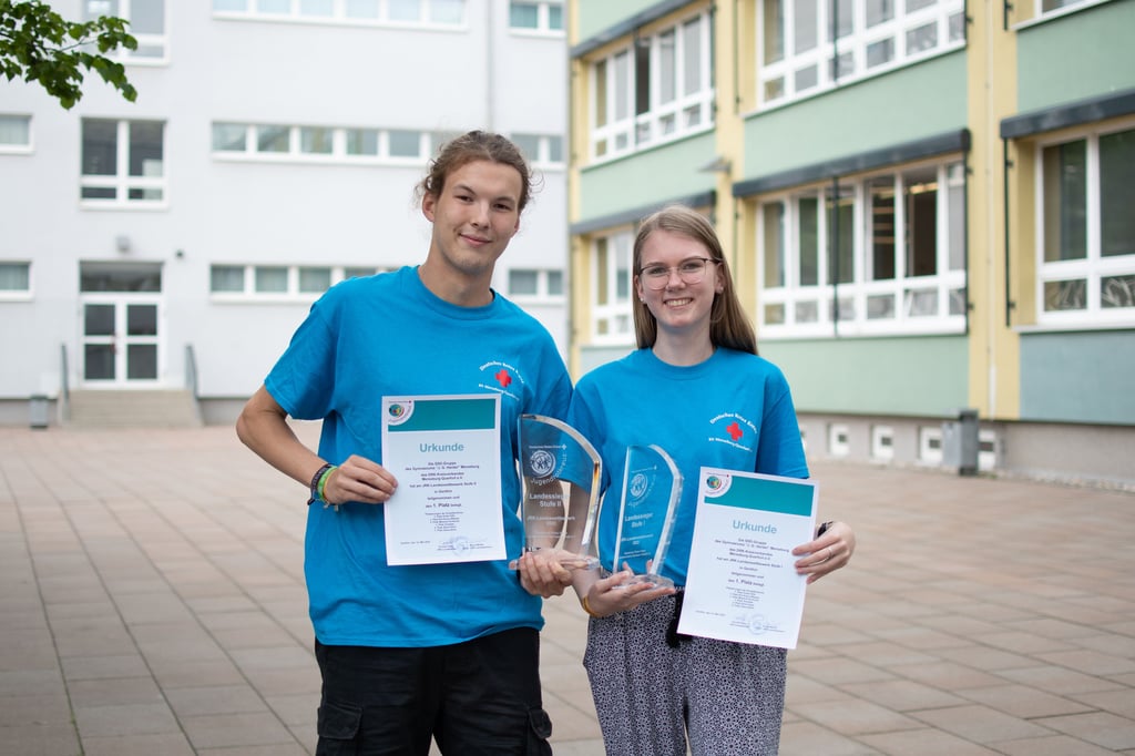Marko Gusowski und Gesa Nieth zeigen auf dem Schulhof des Herder-Gymnasiums stolz ihre Pokale.