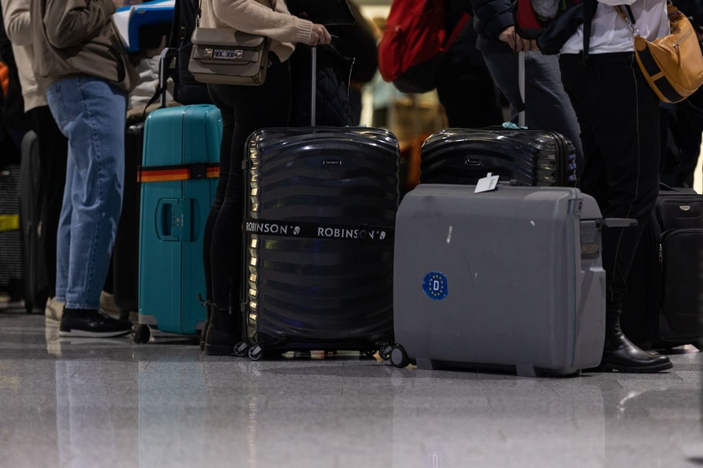Passagiere mit Koffern warten am Check-In Schalter am Frankfurter Flughafen.