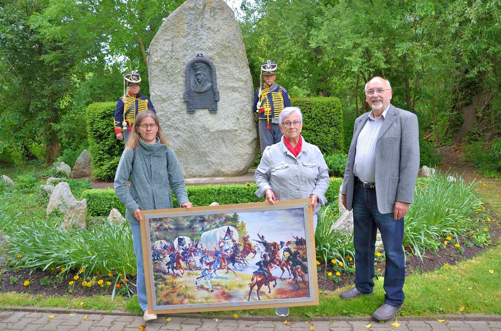 Anlässlich der Feierstunde am Schill-Denkmal in Langenweddingen übergeben Beate Schulze (M.) und Andrea Banz stellvertretend für den Dodendorfer Heimatverein an Jürgen Zimmermann ein Gemälde über die Schlacht von Major Schill.