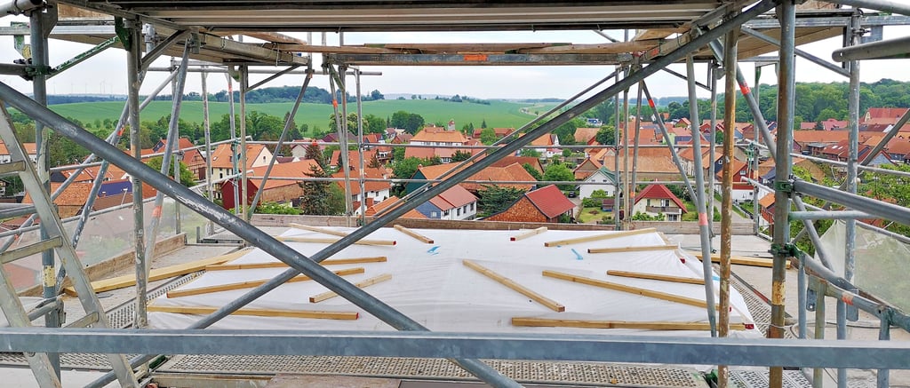 Diesen Ausblick gibt es nur für kurze Zeit: Die Spitze des Berßeler Kirchturms wird derzeit saniert. Solange der Kaiserstiel noch nicht eingesetzt ist, haben die Arbeiter dank Lücken im Holz- und dem Baugerüst einen ungewöhnlichen Blick über das Dorf.