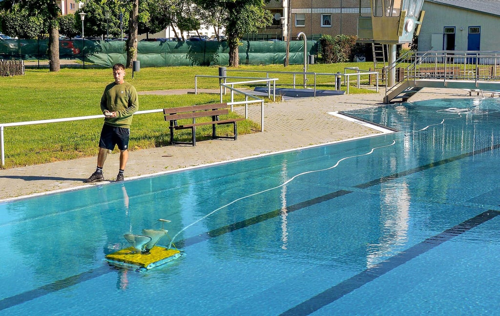 Schwimmmeister Gino Hellrung steuert den Reinigungssaugroboter am Beckenboden des Spaßbades.
