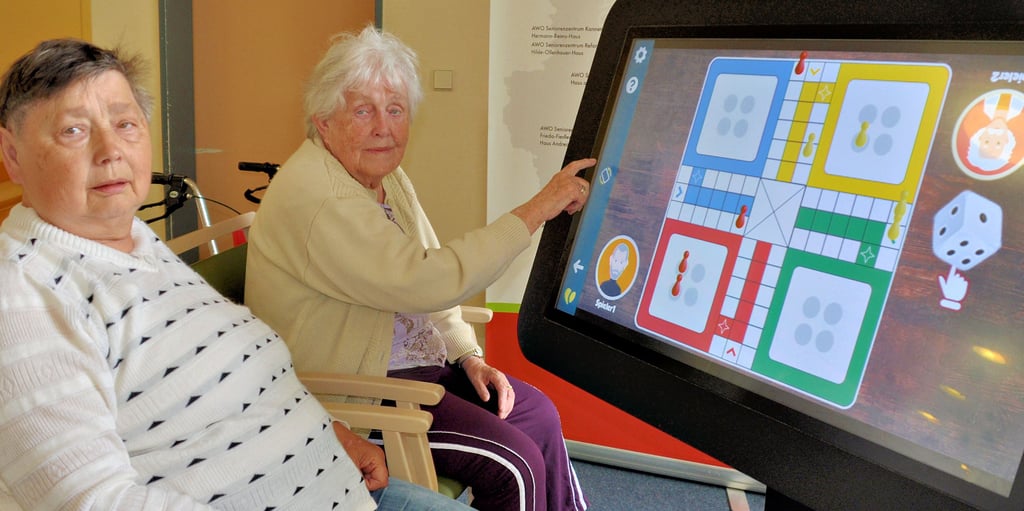 Klara Piontek und Marianne Galgan leben im Hermann-Beims-Haus der Awo im Neuen Sülzeweg in Magdeburg. Wenn sie sich im Foyer des Hauses treffen, dann nehmen sie auch gern einmal an dem großen Bildschirm Platz. An diesem Touch screen liefern sich die beiden dann immer wieder Duelle im virtuellen „Mensch ärgere dich nicht“. Im Angebot sind auch weitere Spiele und – wenn es die Internetverbindung zulässt – der Zugang zu Online-Zeitungsangeboten wie dem der Volksstimme.